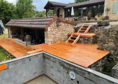 Terrasse en bois devant une maison en pierre